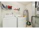 A bright laundry room features white washer and dryer, shelving, and modern water heater at 7048 Tassel Meadow Dr, Indianapolis, IN 46217