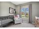 Cozy Bedroom features a white glider, a crib, and a view of the outdoors at 7424 Campfire Run, Indianapolis, IN 46236