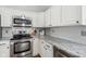 Kitchen with stainless steel appliances, white cabinets, and gray backsplash at 7424 Campfire Run, Indianapolis, IN 46236