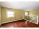 Open hallway with hardwood floors, two windows, and glass railing looking down the stairs at 7640 Bay Shore Dr, Indianapolis, IN 46240