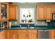 Bright kitchen features wood cabinetry, stainless steel appliances, and garden window with plants at 7640 Bay Shore Dr, Indianapolis, IN 46240