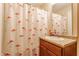 Bathroom with flamingo-themed shower curtain, wood cabinet, and granite counters at 7782 Rose Ln, Ingalls, IN 46048