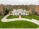 Majestic home showcases a pristine lawn, circular driveway, and elegant facade, surrounded by lush greenery at 8155 Hunt Club Rd, Zionsville, IN 46077