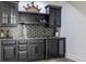 Basement bar features dark cabinetry, stone countertop and hexagon tile backsplash at 8155 Hunt Club Rd, Zionsville, IN 46077