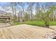 Large backyard with a wooden deck, green grass, storage shed, and bordered by a wood fence and mature trees at 8715 Kensington Dr, Noblesville, IN 46060