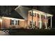 Charming brick home at night featuring white columns, black shutters, and a manicured lawn with mature trees at 8715 Kensington Dr, Noblesville, IN 46060