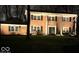 Night view of a brick two story home with black shutters, white columns, and a well maintained lawn at 8715 Kensington Dr, Noblesville, IN 46060