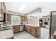 Well-lit kitchen offers wooden cabinetry, stainless steel appliances, and an open view of the living area at 8715 Kensington Dr, Noblesville, IN 46060