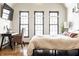 Bright bedroom featuring natural light from three large windows, a desk, and hardwood floors at 933 Tecumseh St, Indianapolis, IN 46201