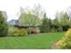 A well-maintained backyard with lush green grass, mature trees, decorative bushes, and a dark wooden fence at 10235 Normandy Way, Fishers, IN 46040