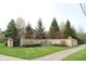 Welcoming community entrance with stone signage, manicured lawn, and mature trees at 10235 Normandy Way, Fishers, IN 46040