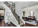 Elegant staircase with wrought iron railing leading to a dining room with chandelier and dark hardwood floors at 10235 Normandy Way, Fishers, IN 46040