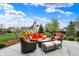 Inviting outdoor patio seating with orange cushions, complemented by lush landscaping and a clear blue sky at 10235 Normandy Way, Fishers, IN 46040