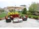 A cozy patio featuring an outdoor seating set, a table with wine glasses, an umbrella, and lush landscaping at 10235 Normandy Way, Fishers, IN 46040