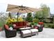 A lovely patio features a rust colored outdoor seating set, a table with wine glasses, and manicured landscaping at 10235 Normandy Way, Fishers, IN 46040