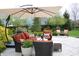 A serene patio with an outdoor seating set, a table with wine glasses, an umbrella, and manicured landscaping at 10235 Normandy Way, Fishers, IN 46040
