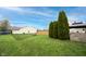 Large backyard featuring green lawn, manicured evergreens, and privacy fence at 12516 Schoolhouse Rd, Fishers, IN 46037