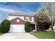Charming two-story home with red shutters, a white garage, lush greenery, and a beautiful blossoming tree at 12516 Schoolhouse Rd, Fishers, IN 46037