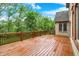Wood deck with railing offers a serene backyard view of lush trees and a brick house exterior at 13758 Foxdale Lake Dr, Carmel, IN 46032