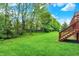 Lush green backyard featuring an expansive lawn and a wooden deck with stairs at 13758 Foxdale Lake Dr, Carmel, IN 46032