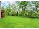 Expansive green backyard with mature trees and a wooden deck visible on the side of the house at 13758 Foxdale Lake Dr, Carmel, IN 46032