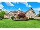 Stunning stone home with lush landscaping, mature trees, and a well-manicured lawn at 13758 Foxdale Lake Dr, Carmel, IN 46032