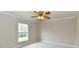 A cozy bedroom featuring neutral walls, plush carpeting, a window, and a lighted ceiling fan at 13858 Meadow Lake Dr, Fishers, IN 46038