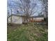 View of the backyard with a deck, boarded-up doors and windows, and overgrown grass at 1704 E Kirk St, Muncie, IN 47303