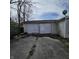 View of the exterior garage doors with a cracked driveway leading up to them at 1704 E Kirk St, Muncie, IN 47303