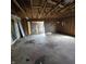 Spacious garage interior with concrete flooring, exposed ceiling, and a partially open doorway leading outside at 1704 E Kirk St, Muncie, IN 47303
