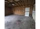 Unfinished garage interior with exposed beams, concrete floor, and a door to the exterior at 1704 E Kirk St, Muncie, IN 47303