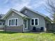Charming single-story home with gray siding, white trim, a brick accent, and a small front patio with seating at 1749 E 52Nd St, Indianapolis, IN 46205