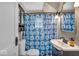 Cozy bathroom features a blue patterned shower curtain, vanity with sink, and built in storage shelves at 1917 W 58Th St, Indianapolis, IN 46228