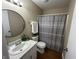Well-lit bathroom features a modern round mirror, white vanity, and shower with decorative gray curtain at 2344 Orchard Creek Dr, Columbus, IN 47201
