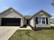 Charming single-story home with a brick facade, black garage door, and well-manicured lawn at 2344 Orchard Creek Dr, Columbus, IN 47201
