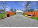 Gravel driveway to a garage, framed by a red-stained privacy fence, green lawn, and a small deck with an outdoor lounge at 2428 N Gale St, Indianapolis, IN 46218