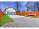Spacious gravel driveway leading to a garage with lawn, a red-stained deck, and a privacy fence at 2428 N Gale St, Indianapolis, IN 46218