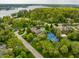 Aerial view of luxury home with a pool, tennis court, mature trees, and lake in the background at 290 Breakwater Dr, Fishers, IN 46037
