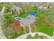 Aerial shot of a beautiful brick home with a pool and tennis court amidst lush greenery at 290 Breakwater Dr, Fishers, IN 46037