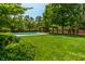 Large backyard with a well-manicured lawn, mature trees, and a pool at 290 Breakwater Dr, Fishers, IN 46037