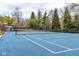 Private backyard tennis court with blue surface, surrounded by mature trees and landscaping at 290 Breakwater Dr, Fishers, IN 46037