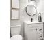 Modern bathroom featuring a round mirror, and white vanity with black hardware and a white toilet at 341 Sanders St, Indianapolis, IN 46225