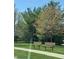 Two benches are sitting on green grass near trees in a community at 4414 Hickory Grove Blvd, Greenwood, IN 46143