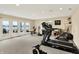 Basement gym with recumbent bike, weight rack, basketball goal, and glass doors leading to the lake at 4883 Snowberry Bay Ct, Carmel, IN 46033