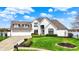 Stunning two-story white brick home with lush landscaping and lake views under a blue sky at 4883 Snowberry Bay Ct, Carmel, IN 46033