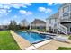 A view of the backyard pool on a sunny day shows the surrounding lawn and lake beyond at 4883 Snowberry Bay Ct, Carmel, IN 46033