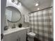 Well-lit bathroom showcasing a vanity with a round mirror and a shower featuring a patterned curtain at 4912 Cayman Ct, Columbus, IN 47203