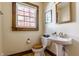 Bright bathroom featuring wood trim, a pedestal sink, and a window with a view of blooming trees at 7124 Purdy St, Indianapolis, IN 46268