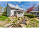 Charming white barn-style building with a rock-lined creek and lush greenery in the yard at 7124 Purdy St, Indianapolis, IN 46268