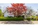 Charming two-story home with gray siding, red maple tree, brick driveway, and manicured front hedge at 7124 Purdy St, Indianapolis, IN 46268